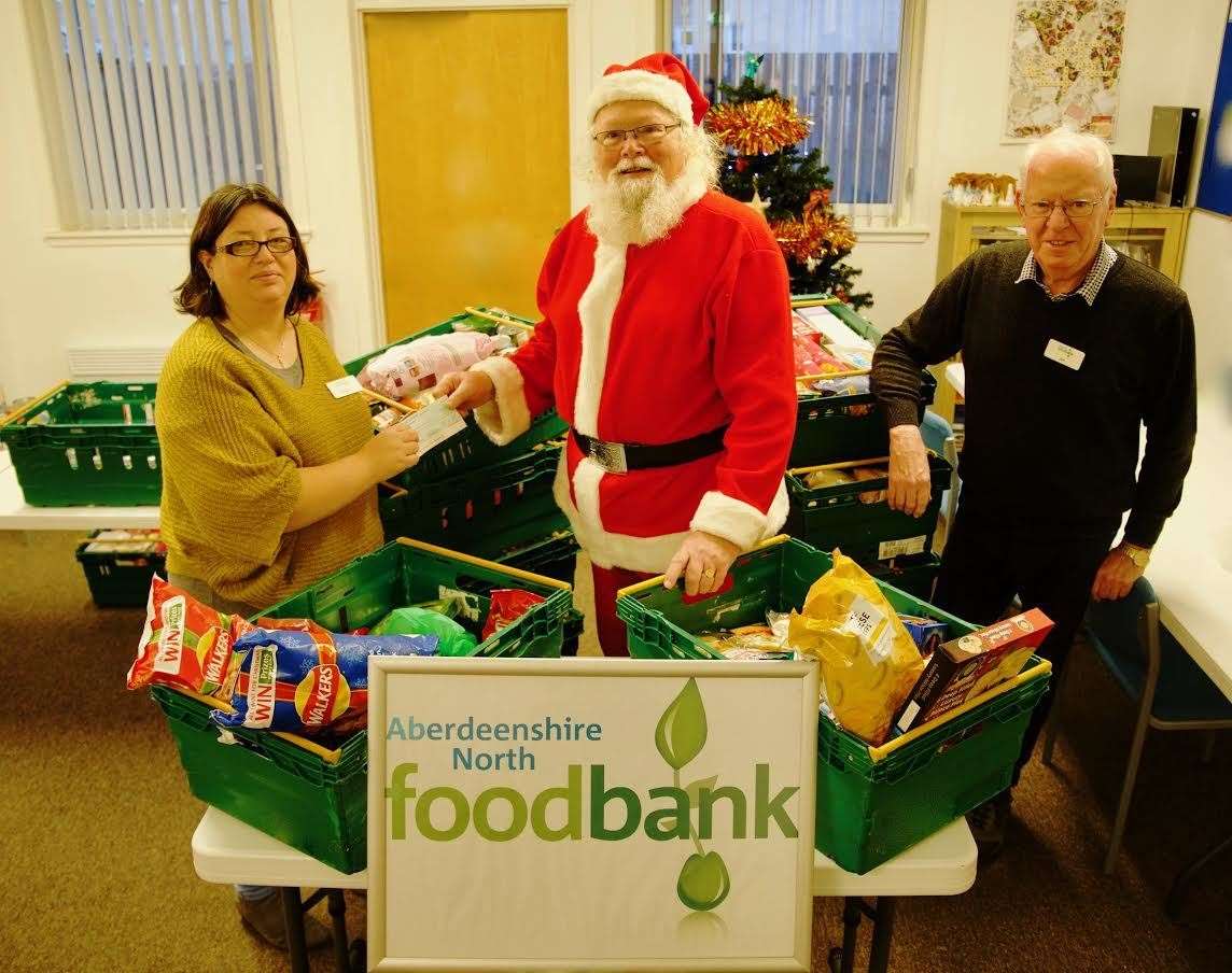 Santa made a donation to the local foodbank on behalf of Ellon Rotary Club, which was accepted by volunteers Karen Butchart and Jim Riley. Picture: Phil Harman
