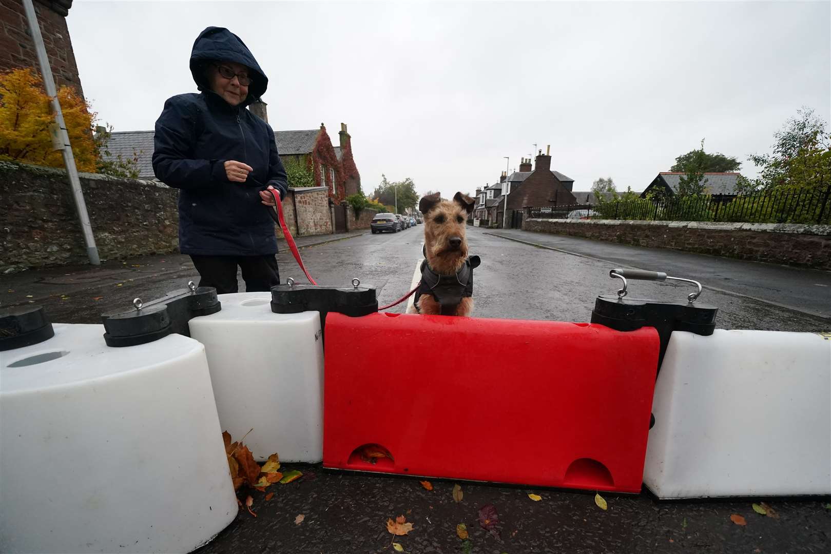 A woman and her dog at a flood defence barrier in Edzell, Scotland (Andrew Milligan/PA)