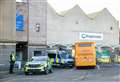 Forensics team at the scene of 58-year-old's death at Elgin Bus Station as floral tributes are paid