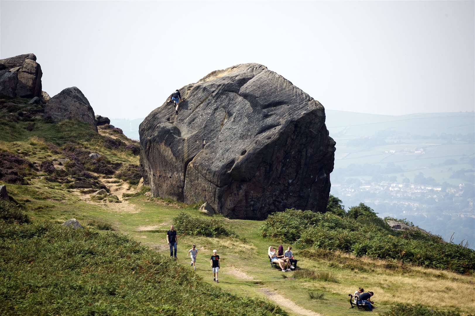 People walk near a rock formation known locally as the Cow and Calf on Ilkley Moor in Yorkshire (PA)