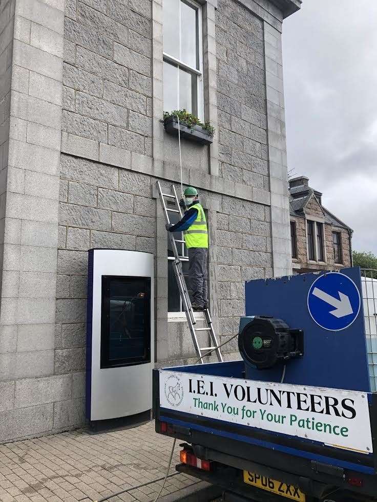 A voluteer for IEI waters the hanging baskets in the town centre