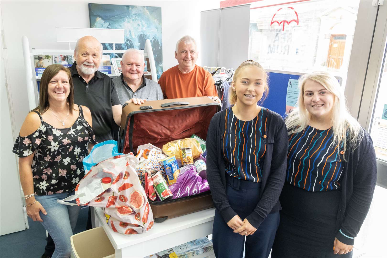 Vykky Johnston (right), Iona Alexander (second right) and Karen Pitt (left) from Hay's Travel hand over the proceeds from the firm's Fill a Suitcase campaign to (back, from left) Gordon McDonald, Ronnie Cargill and Kevin McKay from Buckie Community Hub. Picture: Beth Taylor