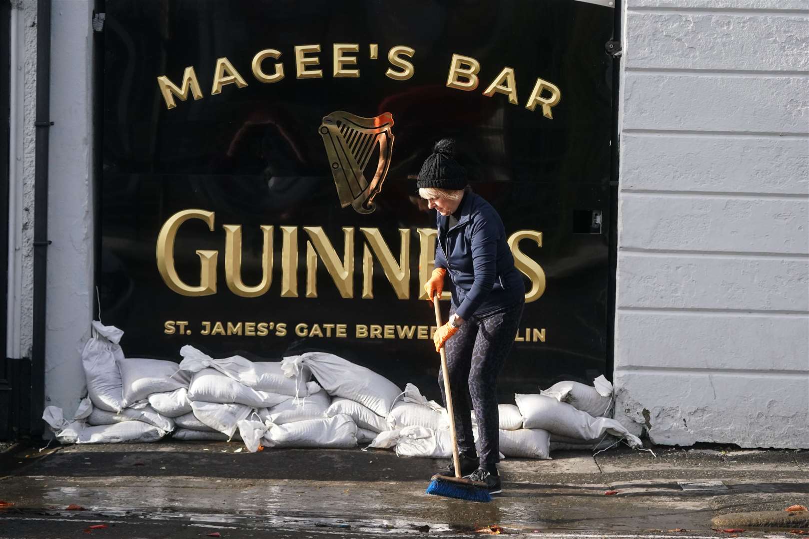 Delia Magee sweeps up outside Magee’s Bar as the clear-up begins in Newry (Brian Lawless/PA)