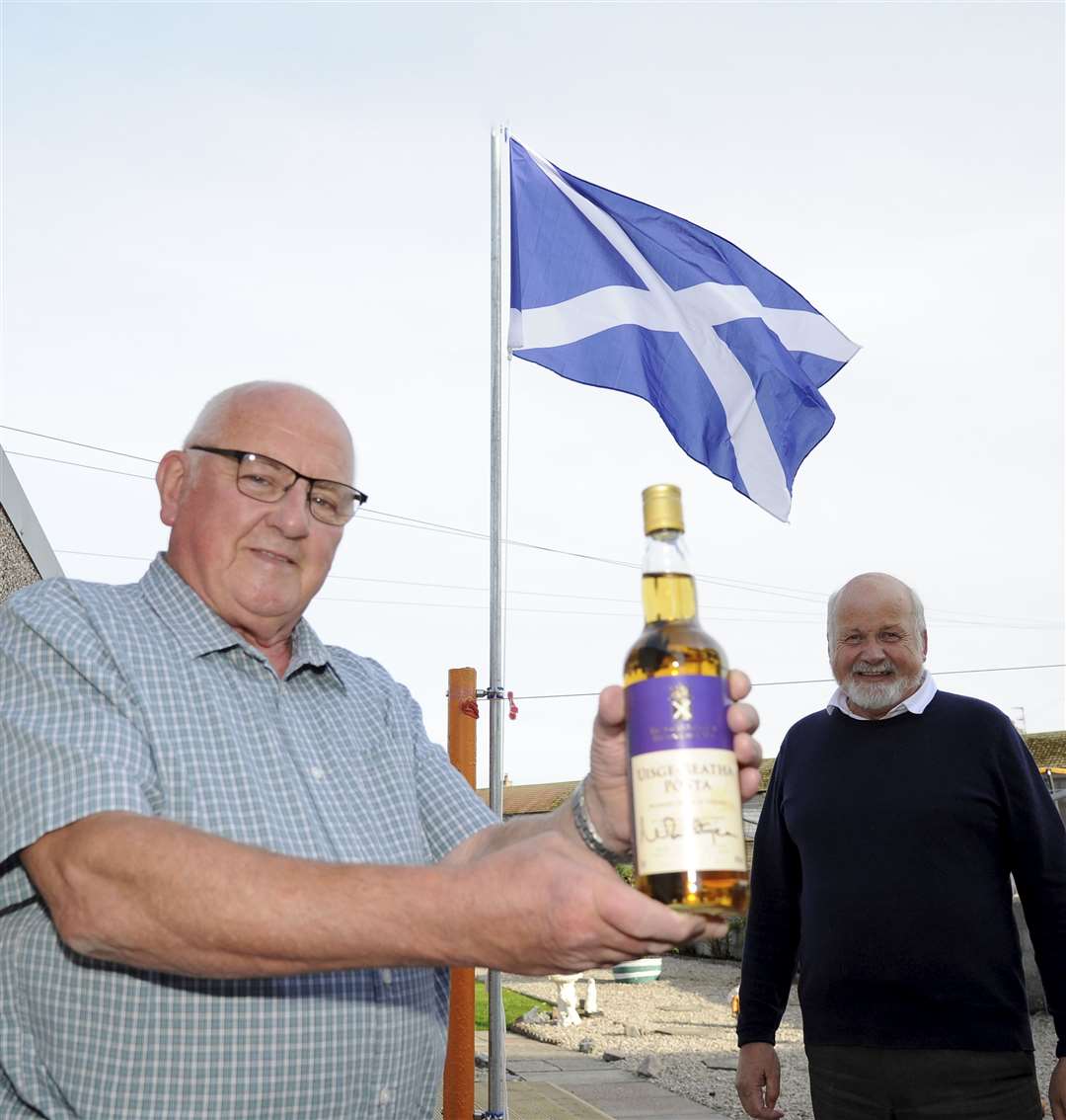 Peter Souter with his bottle of signed Scottish Parliament whisky after being presented with it by Buckie SNP branch convener Gordon McDonald. Picture: Eric Cormack