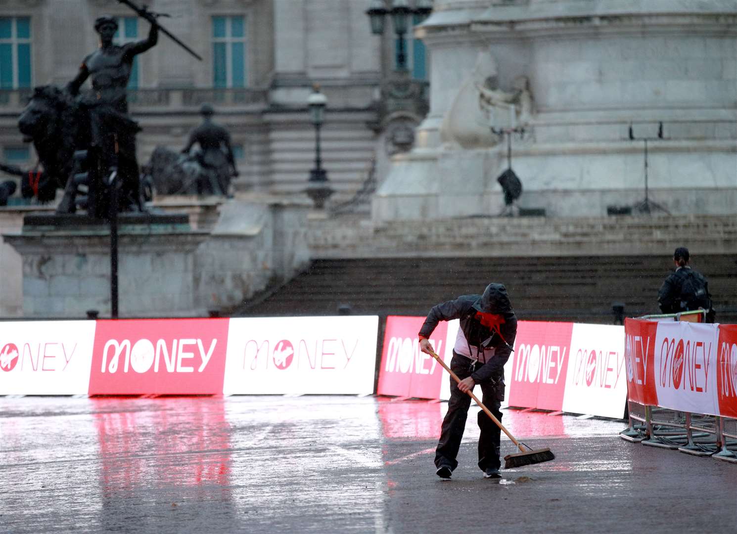 A steward sweeps the course after heavy rain (Ian Walton/PA)
