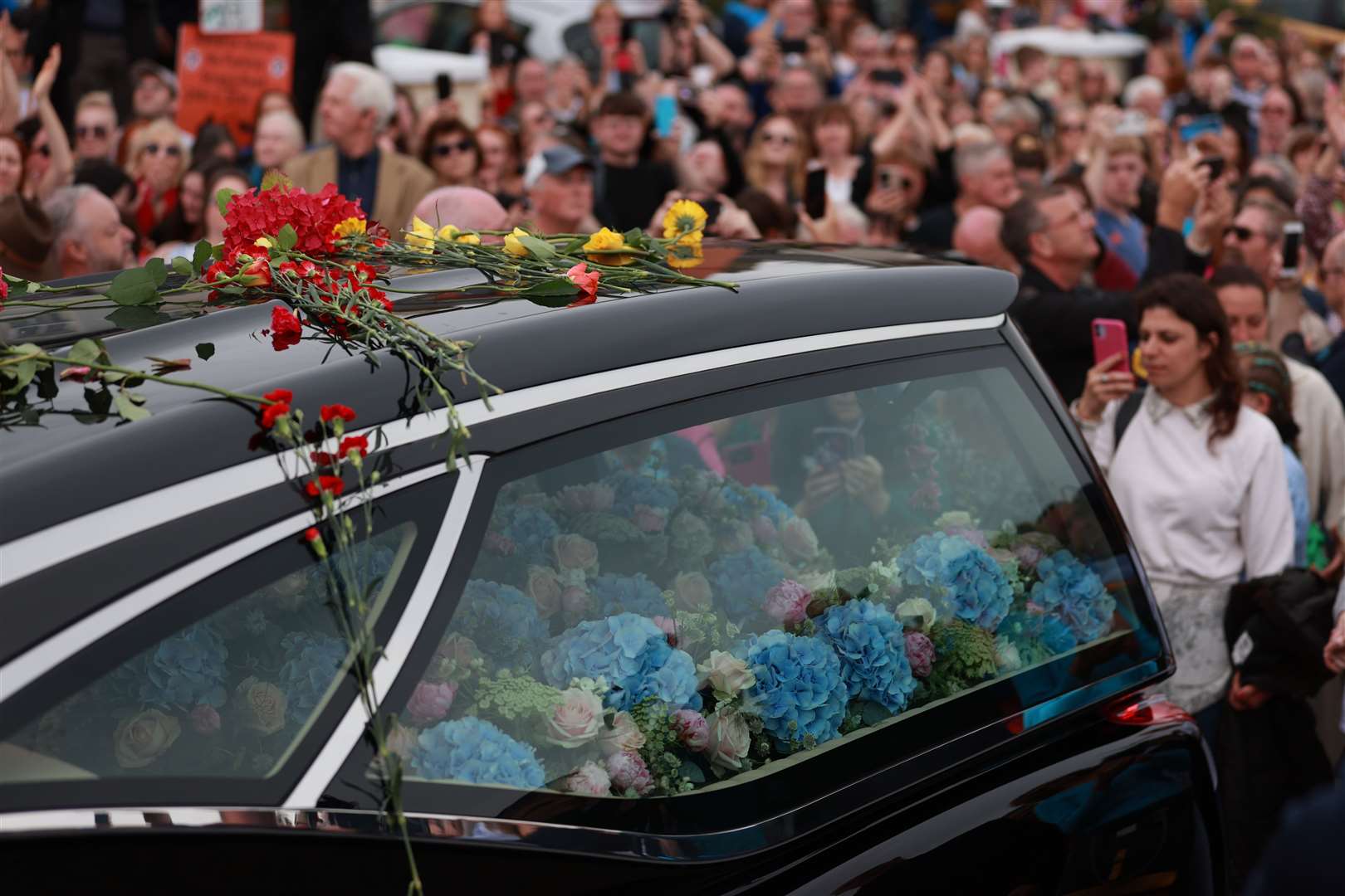 Flowers were thrown at the hearse as it passed by (Liam McBurney/PA)
