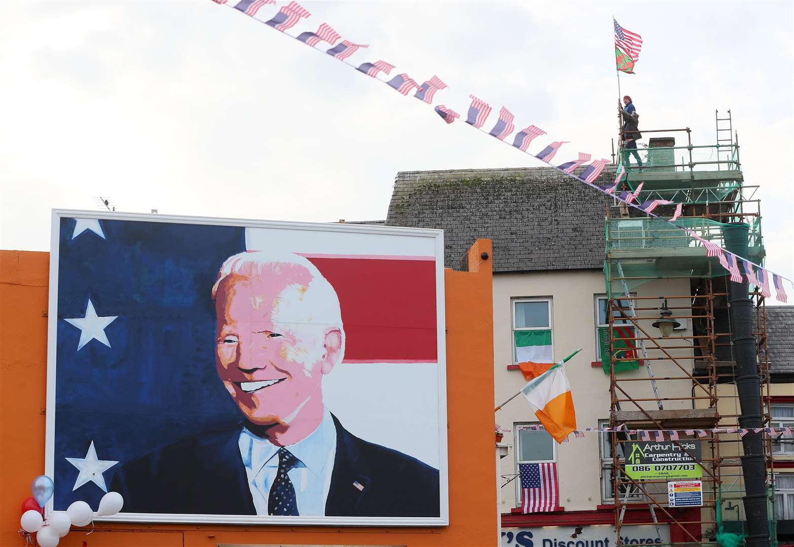Men erect flags on top of a building in Ballina (Brian Lawless/PA)