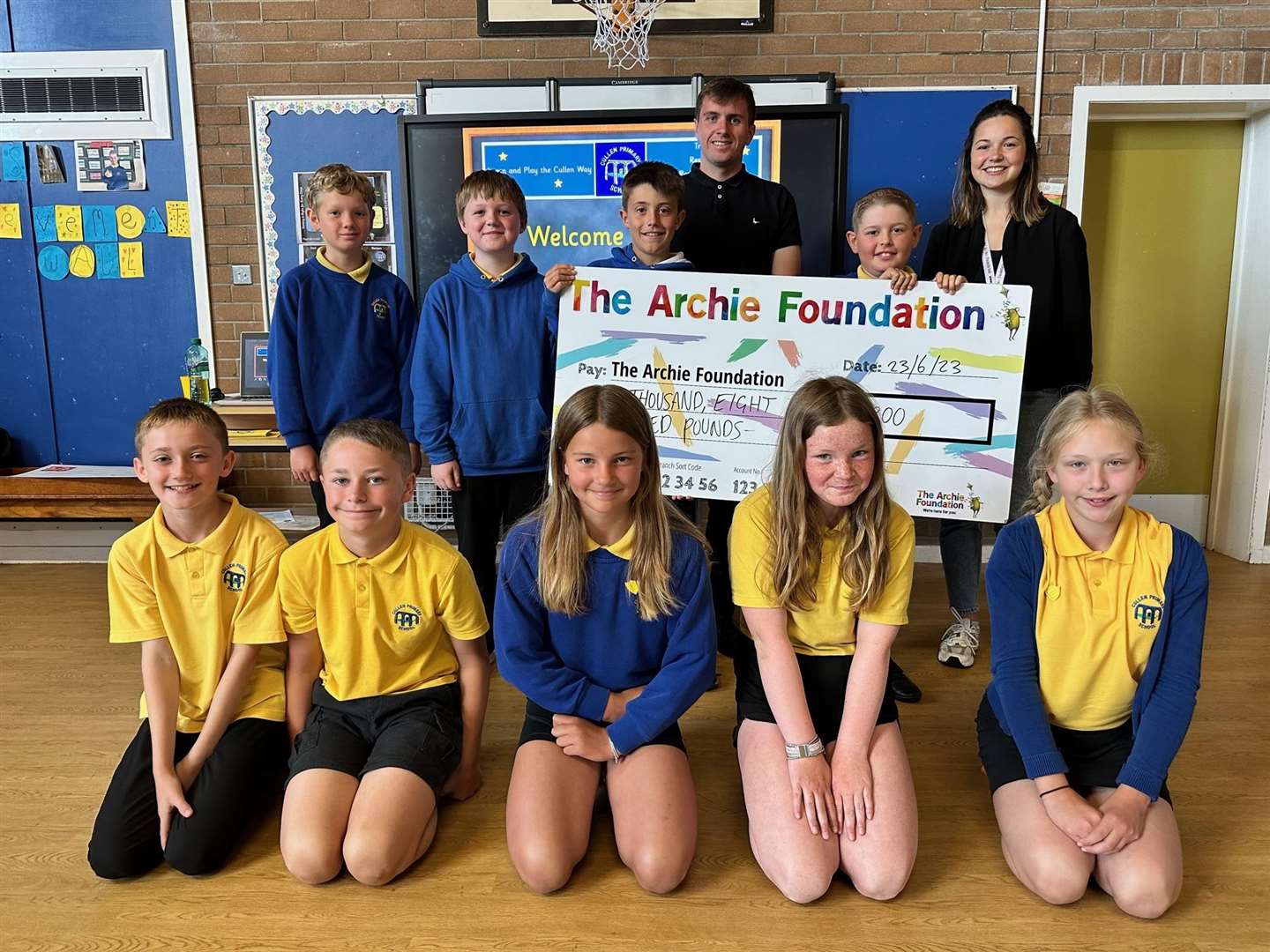 Archie Grampian Regional Fundraising Officer Cassie McGunnigle accepts a cheque for £1800 from Cullen Primary NQT Will Ramsay and some pupils from the school. Picture: Moray Council
