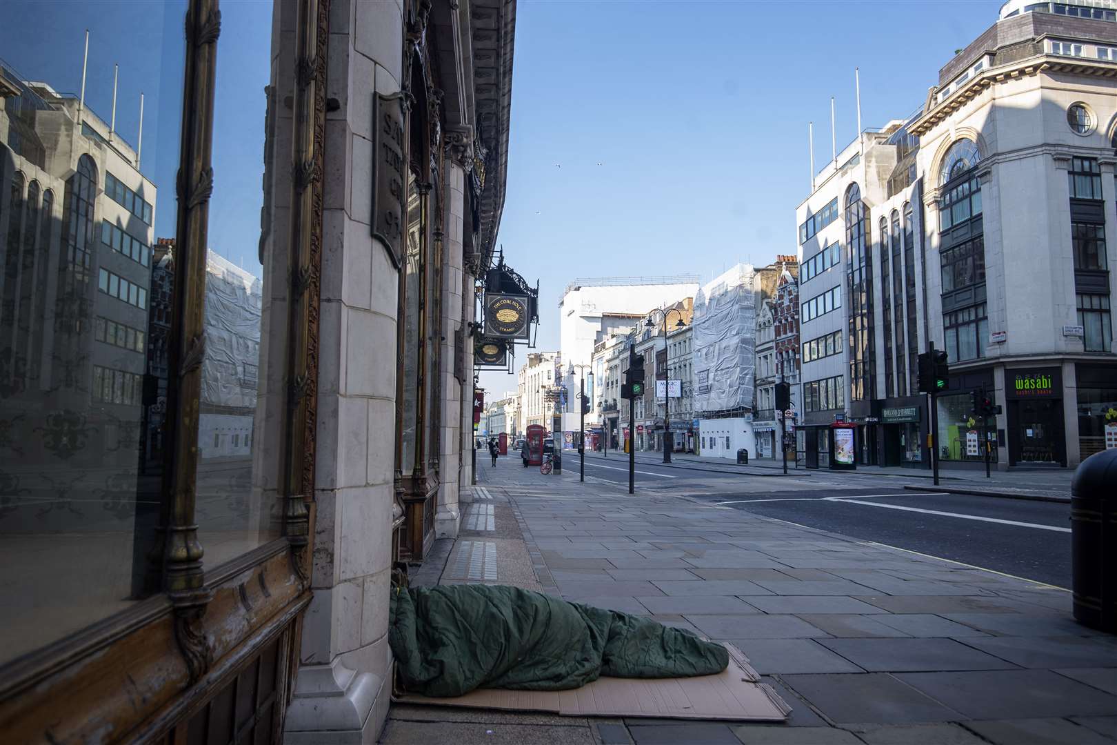 A homeless person lies on the pavement during rush hour on the Strand in Westminster, London (Victoria Jones/PA)