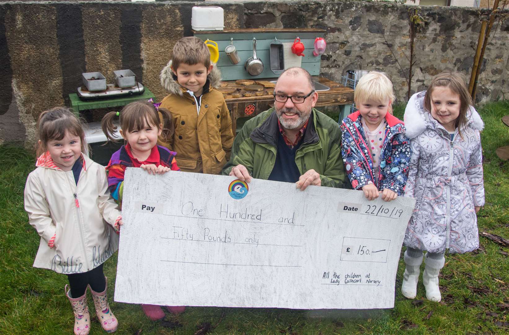 Alistair Webster from Cullen Men's Shed accepts a cheque for £150 from Lady Cathcart nursery pupils (from left) Kaydee Green, Mya-Rose Dougall, Alec Petkov, Abbie Sutherland and Anna Danailova. Picture: Becky Saunderson