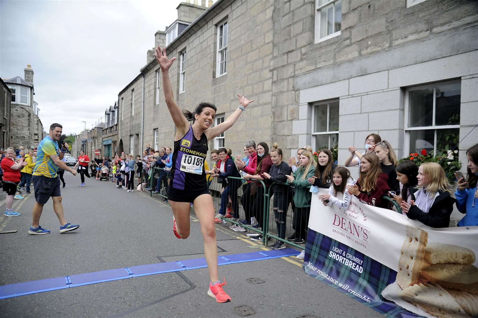 Womens 10k winner Amy Muir leaps over the finish line.