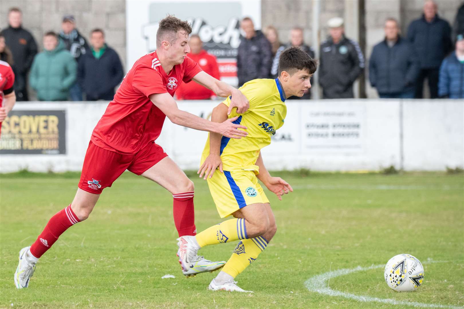 Lossiemouth's Ross Morrison closes in on Buckie's Max Barry. Picture: Daniel Forsyth..