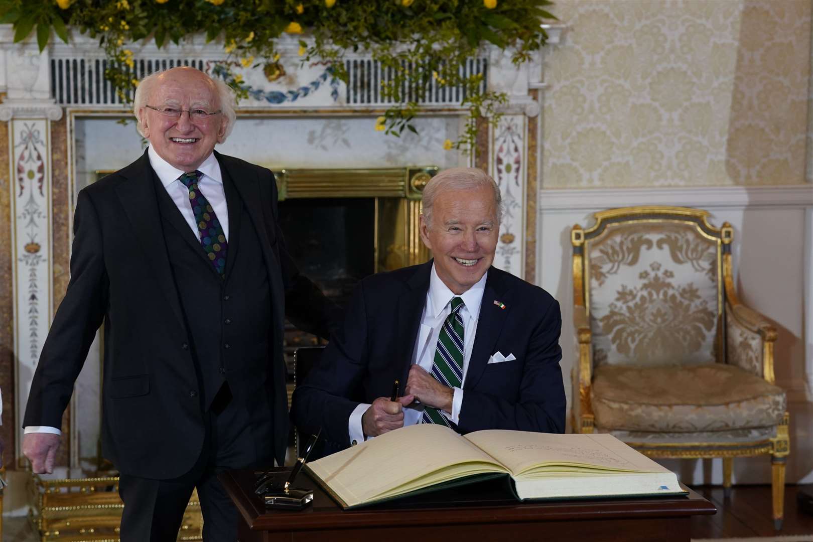 Joe Biden shares a joke with Michael D Higgins as he signs the visitors book at Aras an Uachtarain, in Phoenix Park, Dublin (Brian Lawless/PA)
