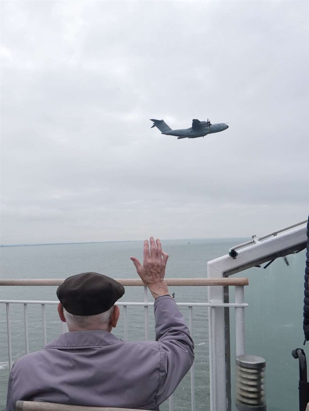 A veteran waves to a Royal Air Force plane over the Brittany Ferries ship Mont St Michel as it sails out of Portsmouth Harbour (Jordan Pettit/PA)