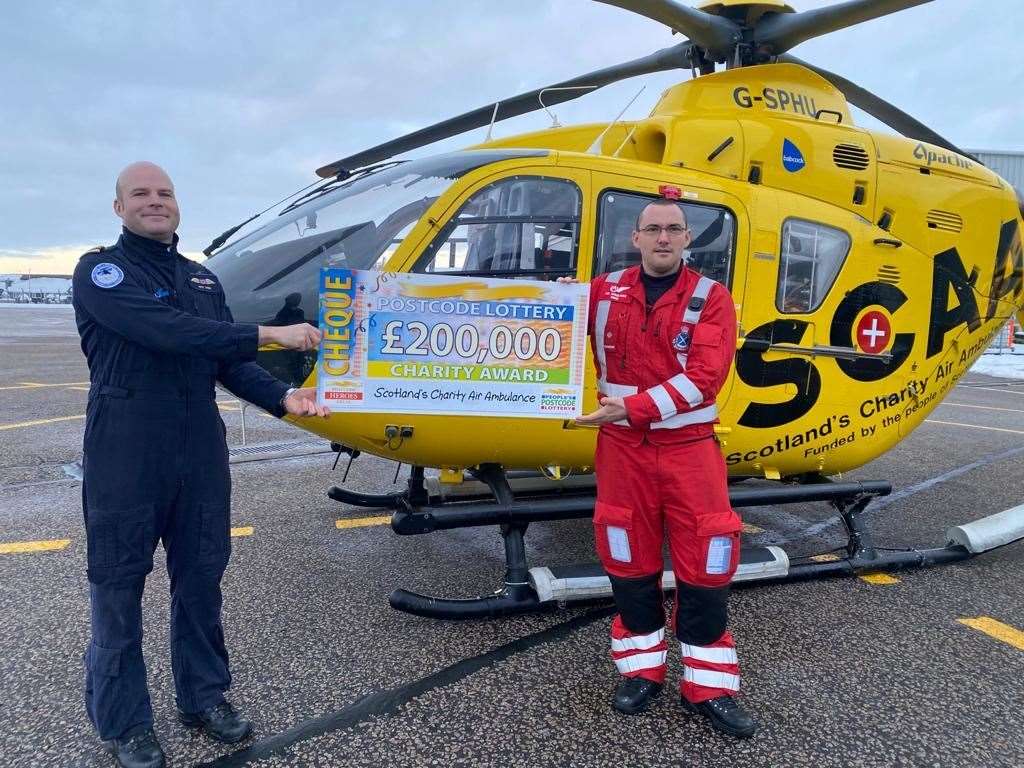 SCAA pilot Captain Pete Winn and Lead Paramedic Ewan Littlejohn with the latest funding award from People's Postcode Lottery.