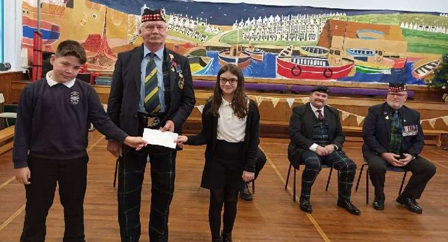P7 Leadership Team members Flynn West-McKay and May Phimister present a cheque to Archie Jamieson from Buckie British Legion. Picture: Findochty Primary