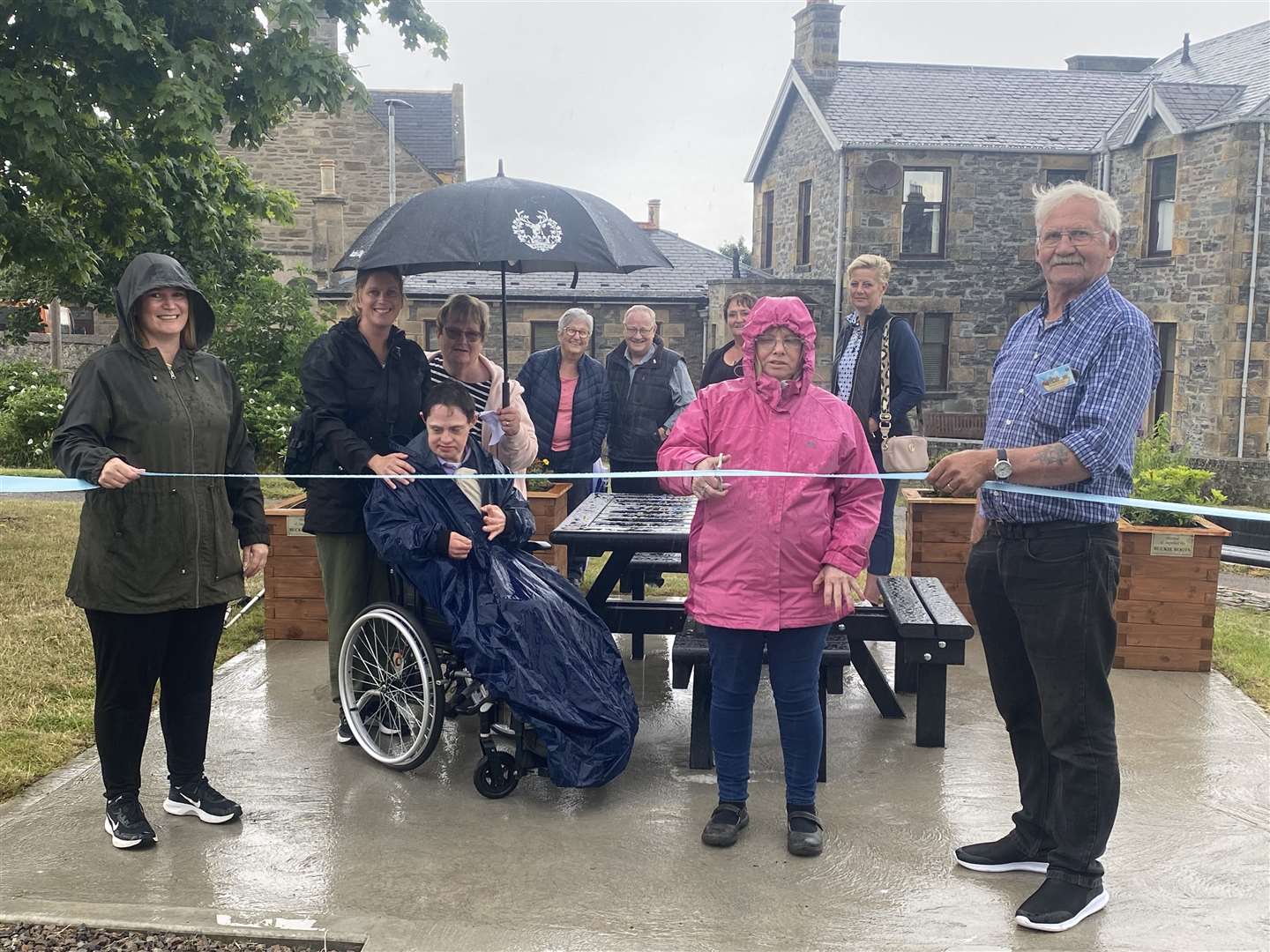 Burnie Centre client Jackie Mainland cuts the ribbon to declare the rest and remembrance area open. She is joined by Buckie's Roots volunteers, and Burnie centre users and carers.