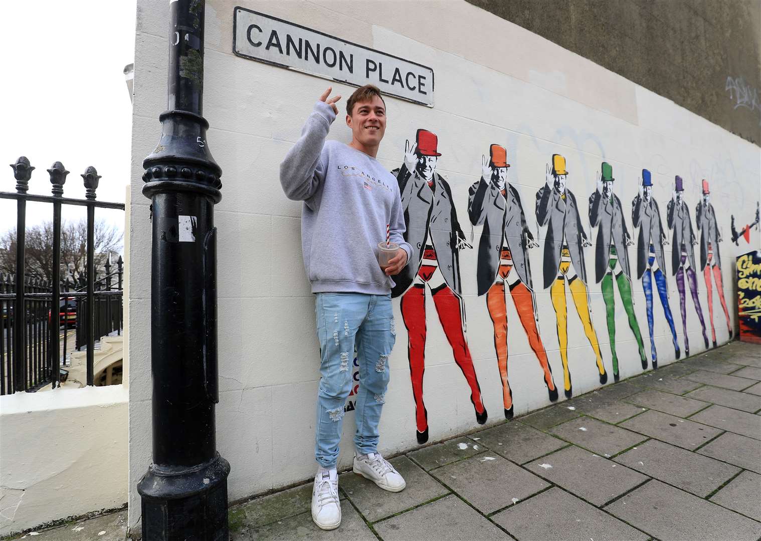 A man poses for a picture next to the mural (Gareth Fuller/PA)