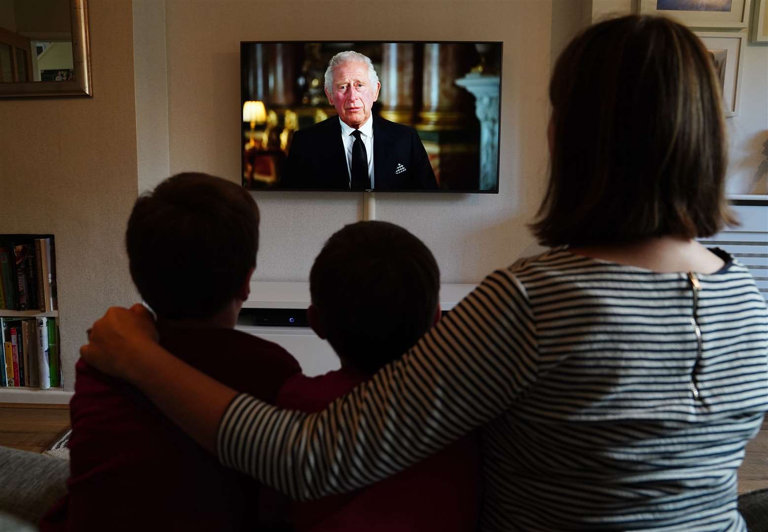 Ben, Isaac and Krystyna Rickett watching a broadcast of the King’s first address to the nation (Martin Rickett/PA)