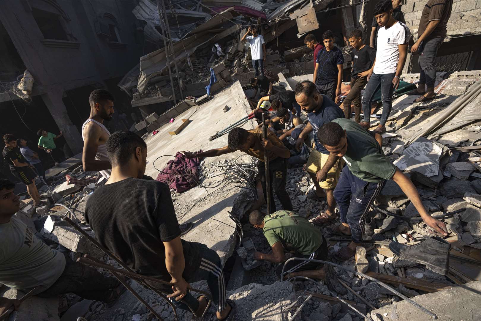Palestinians search for bodies and survivors in the rubble of a residential building levelled in an Israeli airstrike (Fatima Shbair/AP)