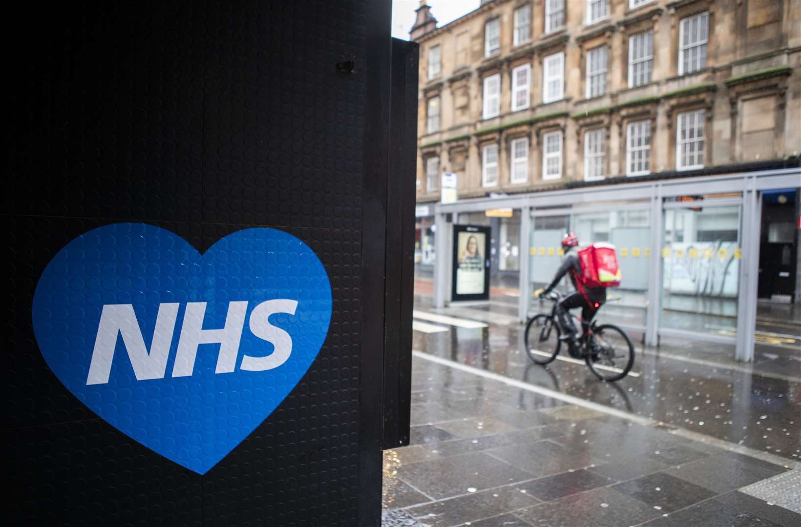A member of the public cycles past an NHS love heart sign in Glasgow (Jane Barlow/PA)