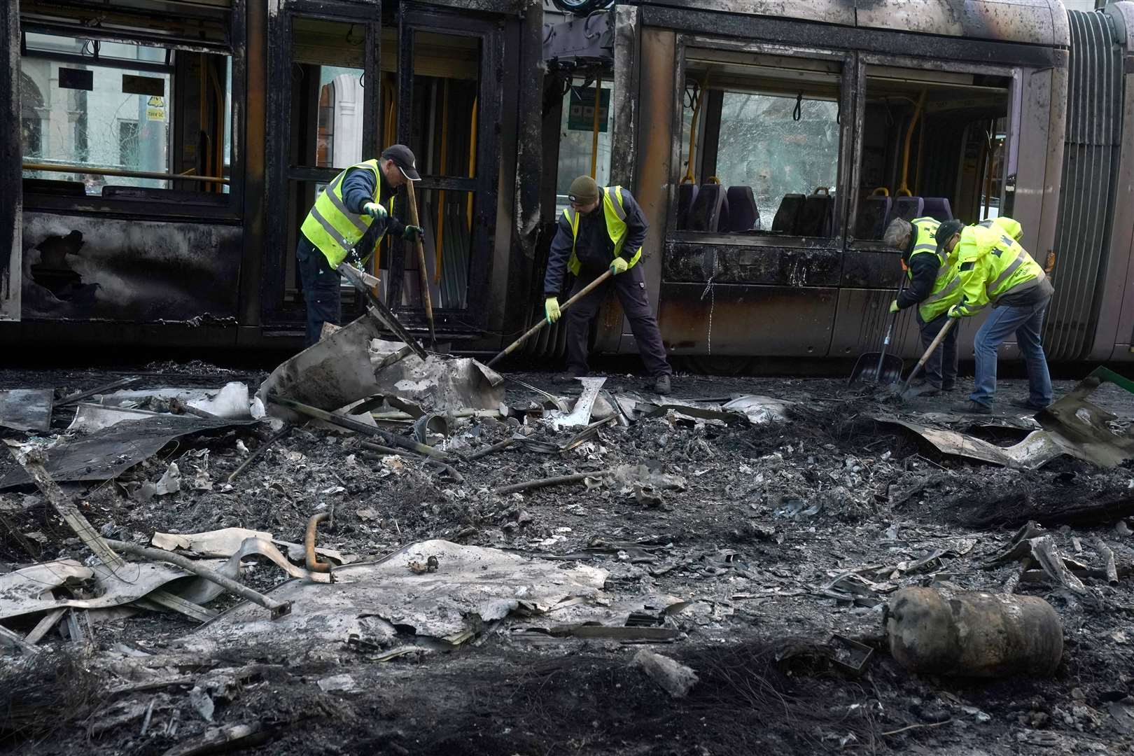 Debris is cleared from a burned out Luas and bus on O’Connell Street (Brian Lawless/PA)