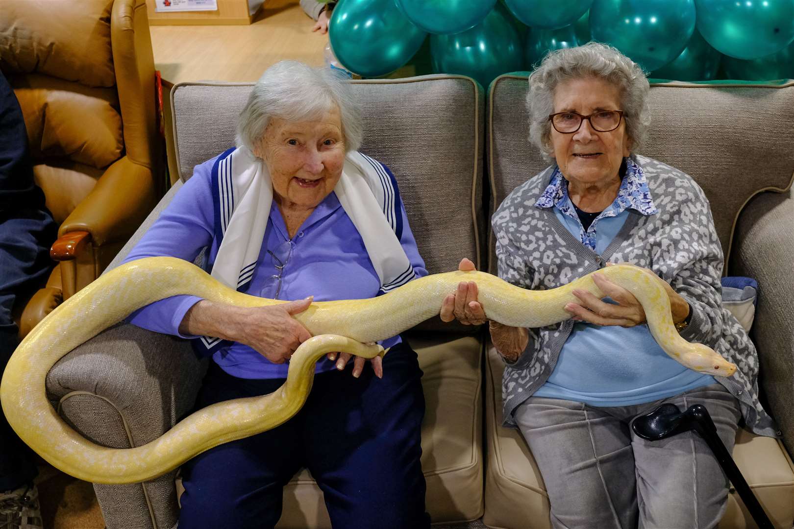Residents Doreen Barber, 96, and Mary Tierney, 92, hold a 6ft-long albino snake as their care home brought I’m A Celebrity… to life for them (Care UK/PA)
