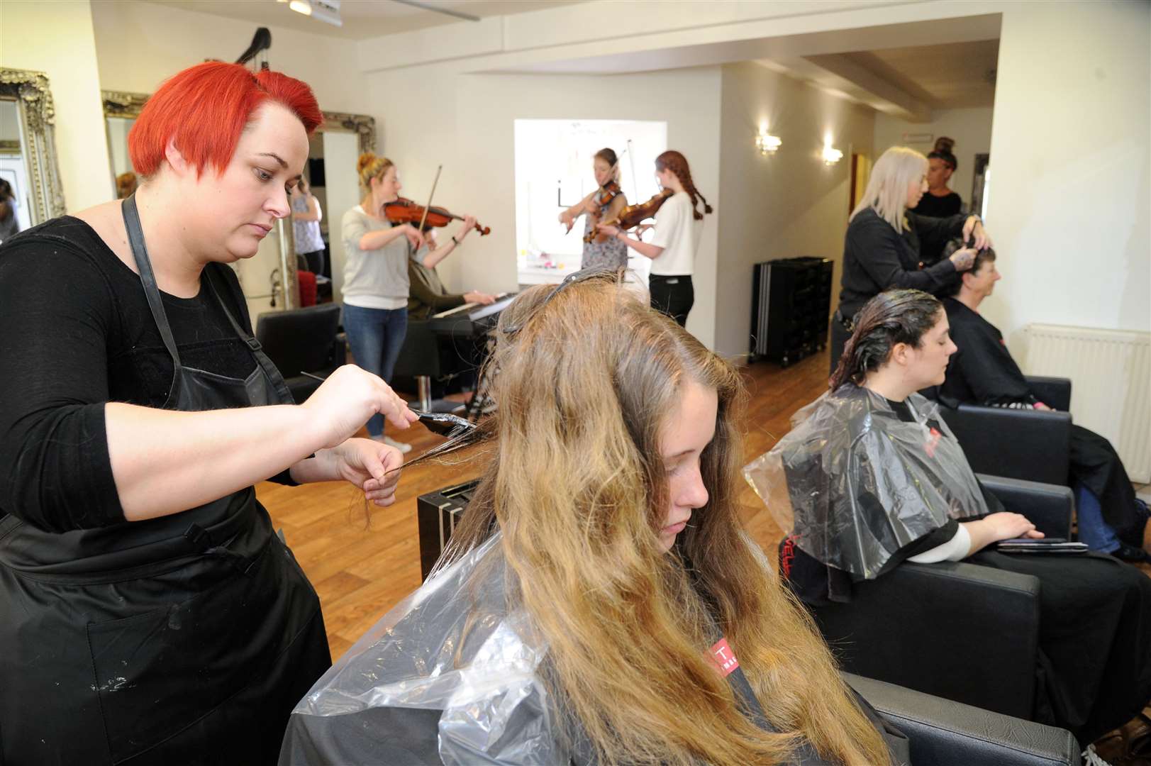 Music while you cut hair. Fochabers Fiddlers entertain customers and hairdresser Hayleigh Main at Shears Hair and Beauty Retreat in Mid Street. Pictures: Eric Cormack. Image No.044187.