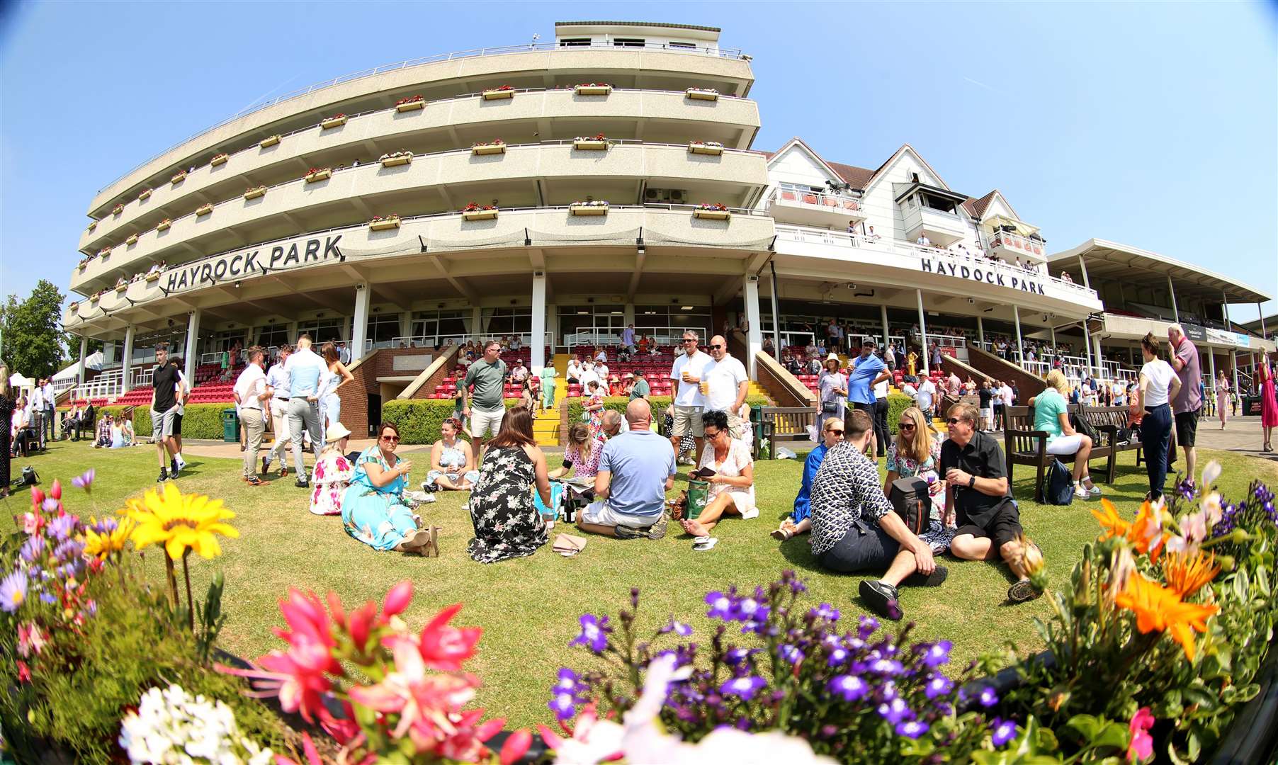 Racegoers enjoy the sun in front of the grandstand before the first race at Haydock Park Racecourse, Merseyside (Nigel French/PA)