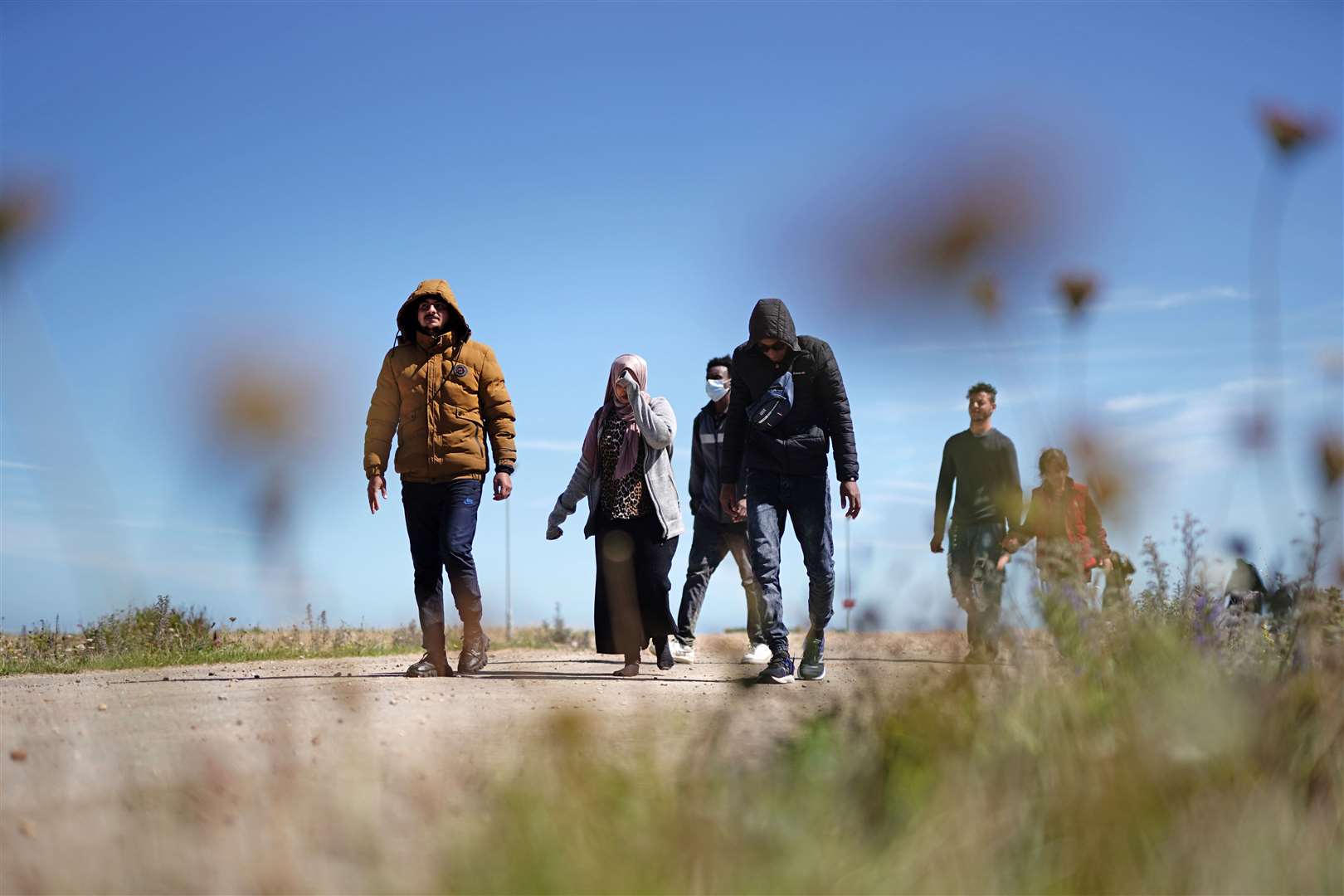 People thought to be migrants walking along the beach after being brought ashore in Dungeness, Kent, on Wednesday (Jordan Pettitt/PA)