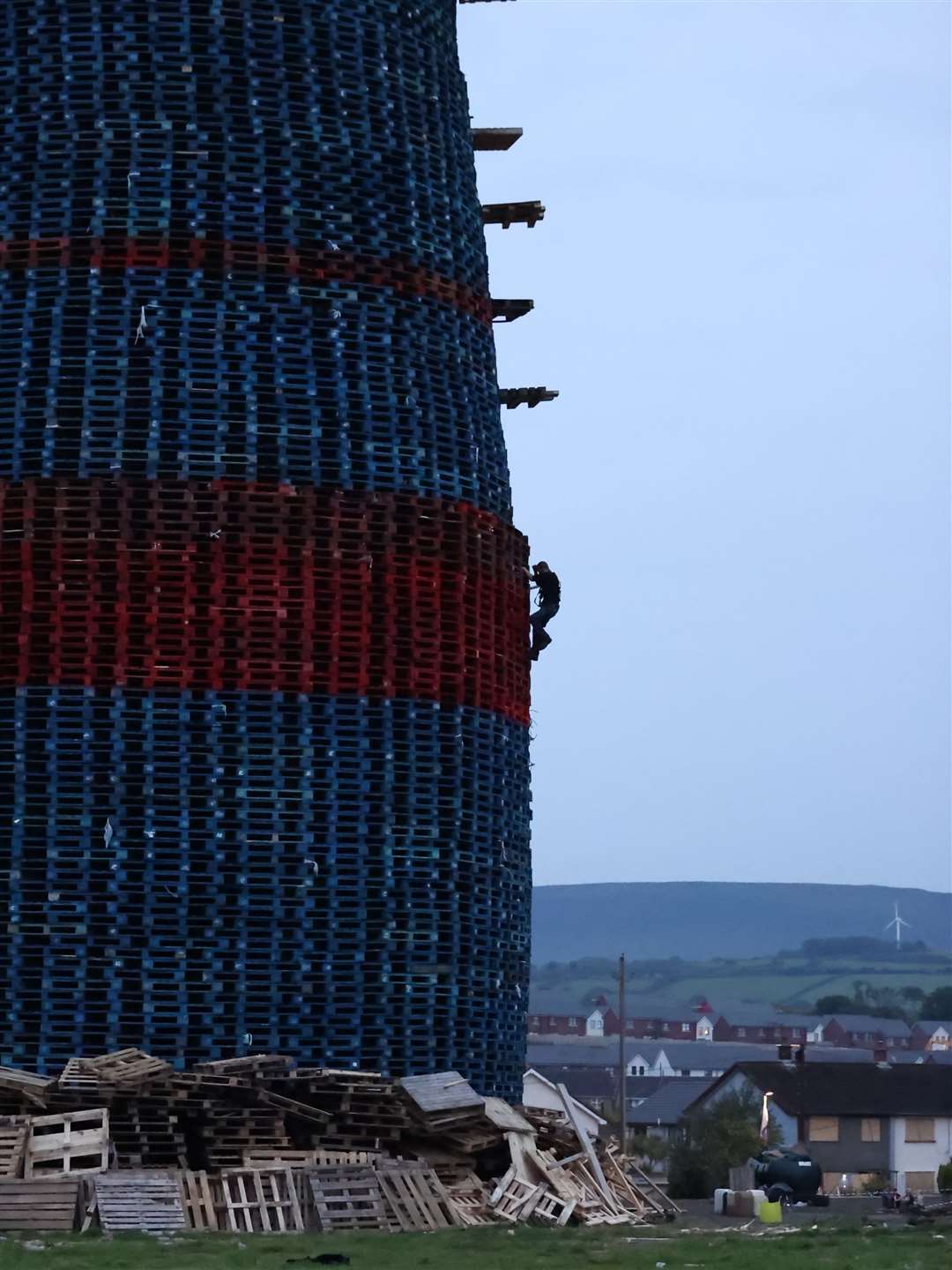 A bonfire builder climbs the side of the Craigyhill bonfire in Larne, as he makes final checks prior to it being lit (Liam McBurney/PA)