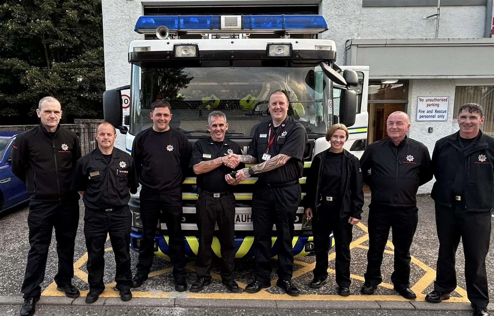 Crew Commander Gary Smith (fourth left) is presented with the service ribbons by Group Commander Davie Hendry as colleagues look on. Picture: Fochabers fire station