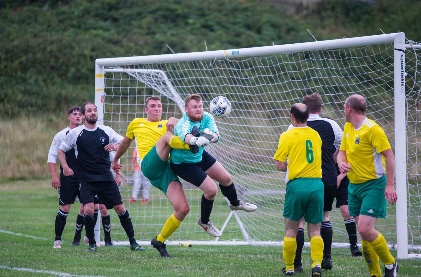 Buckie keeper Ryan Brindle gets the ball clear under pressure from Hopeman's Lee Spencer. Picture: Becky Saunderson..