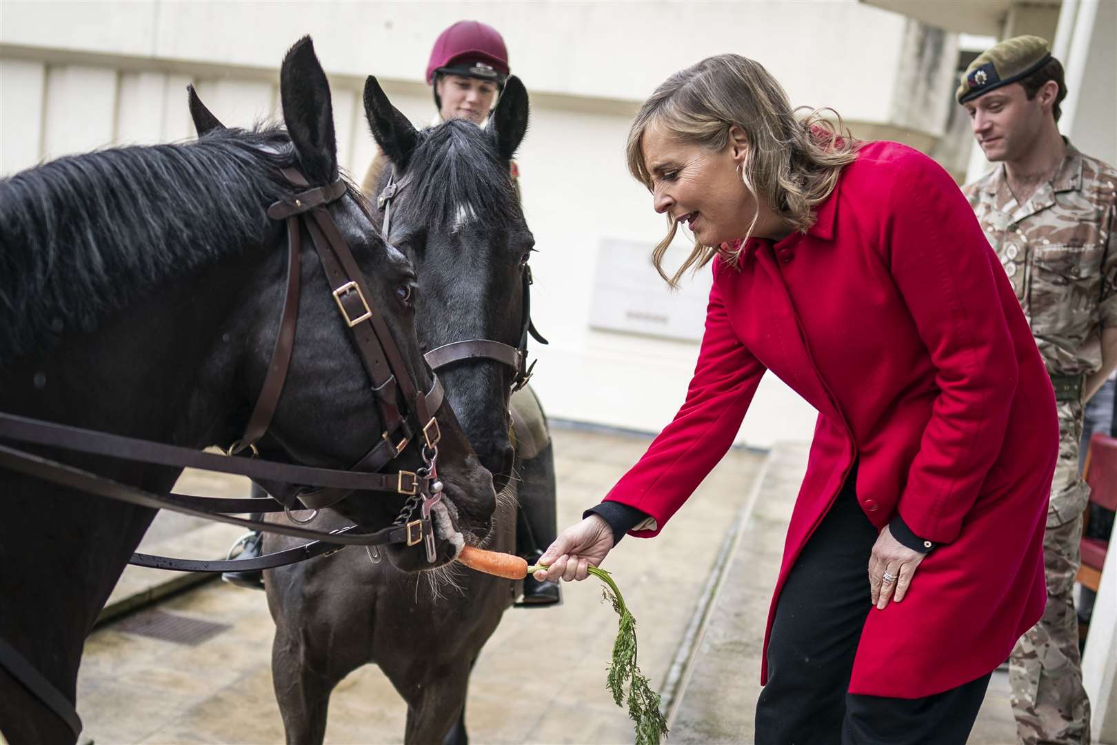 Presenter Mel Geidroyc feeds a carrot to horses Hastings and Warrior (Aaron Chown/PA)