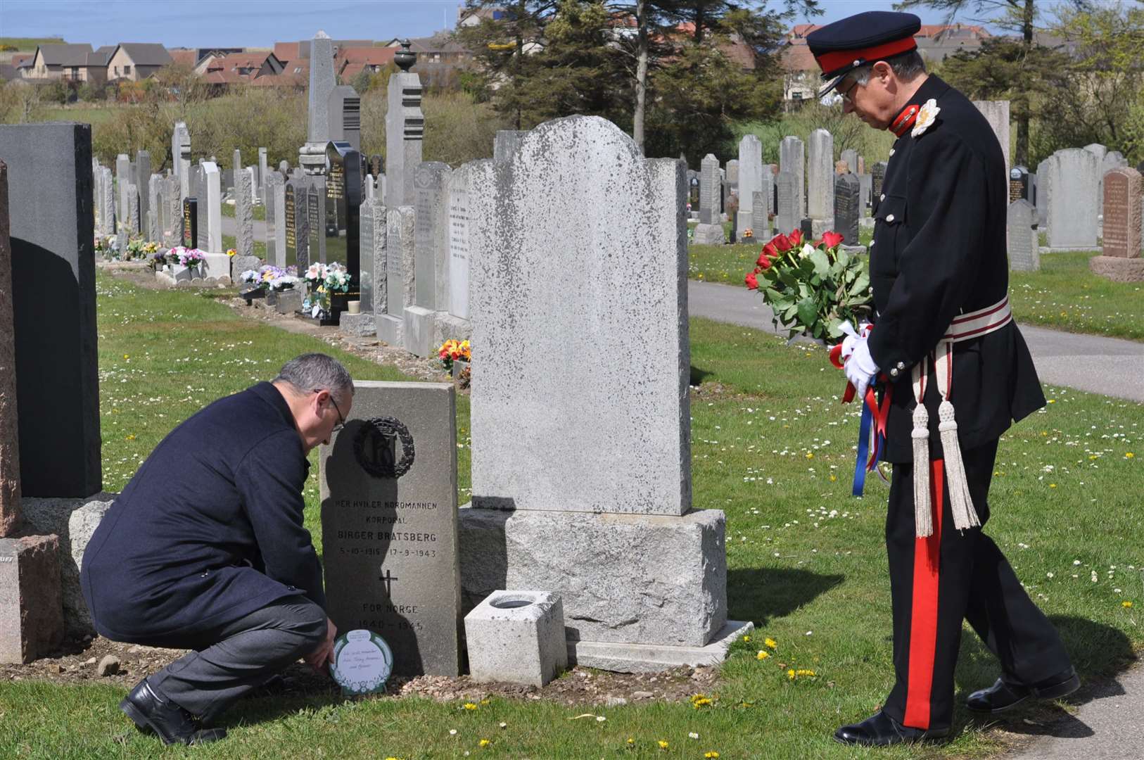 Commonwealth War Graves Commission volunteer Vincent Stuart at the graveside of Birger Bratsberg as Andrew Simpson, Lord Lieutant of Banffshire, watches on.