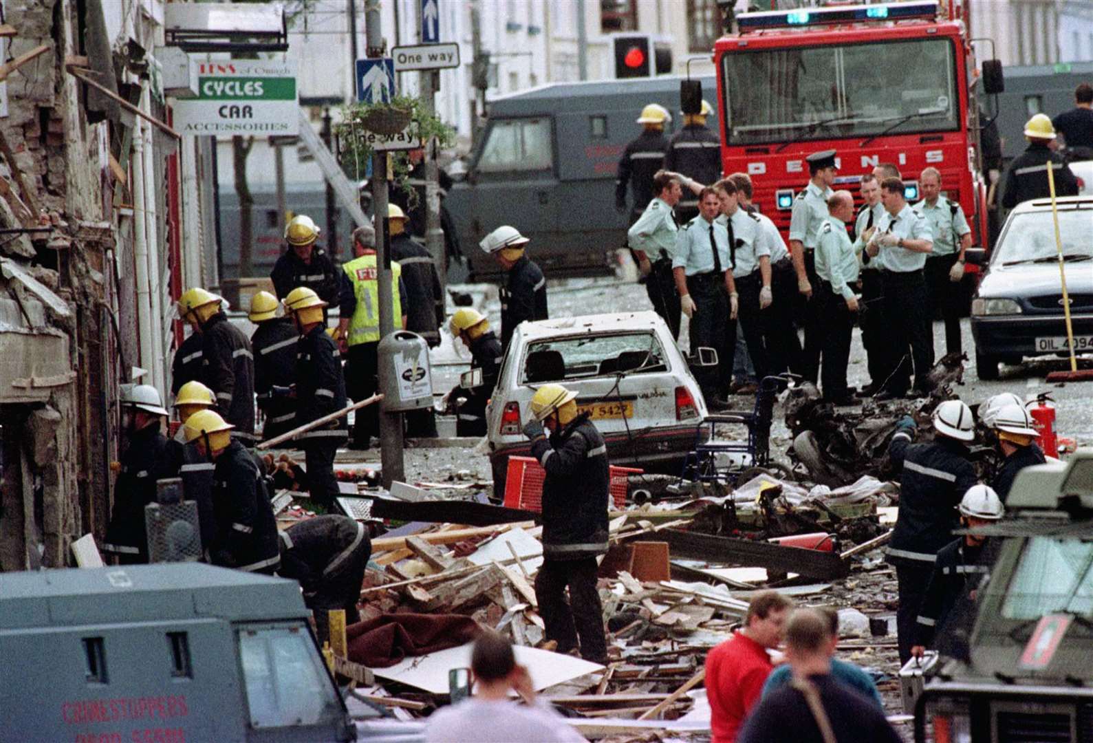 Police officers and firefighters inspect the damage caused by a bomb explosion in Market Street, Omagh (Paul McErlane/PA)
