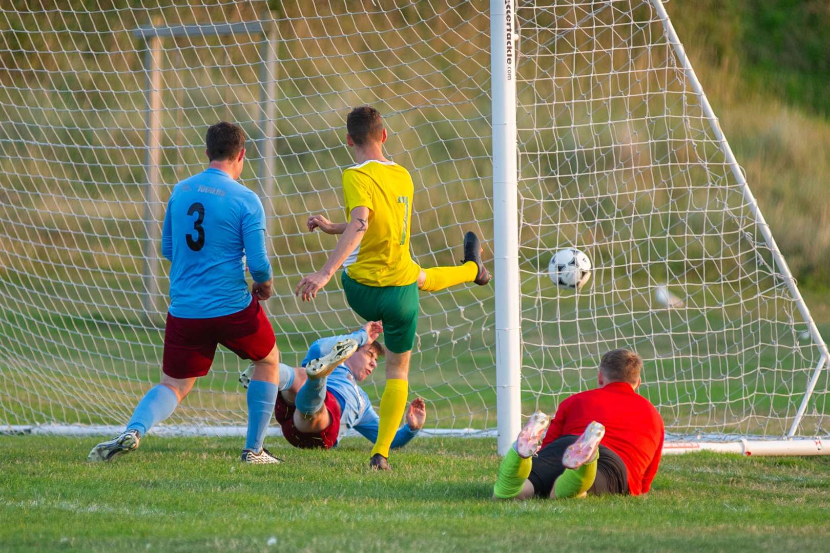 Ryan Farquhar (centre) smashes home his second half goal for Hopeman. Picture: Daniel Forsyth..