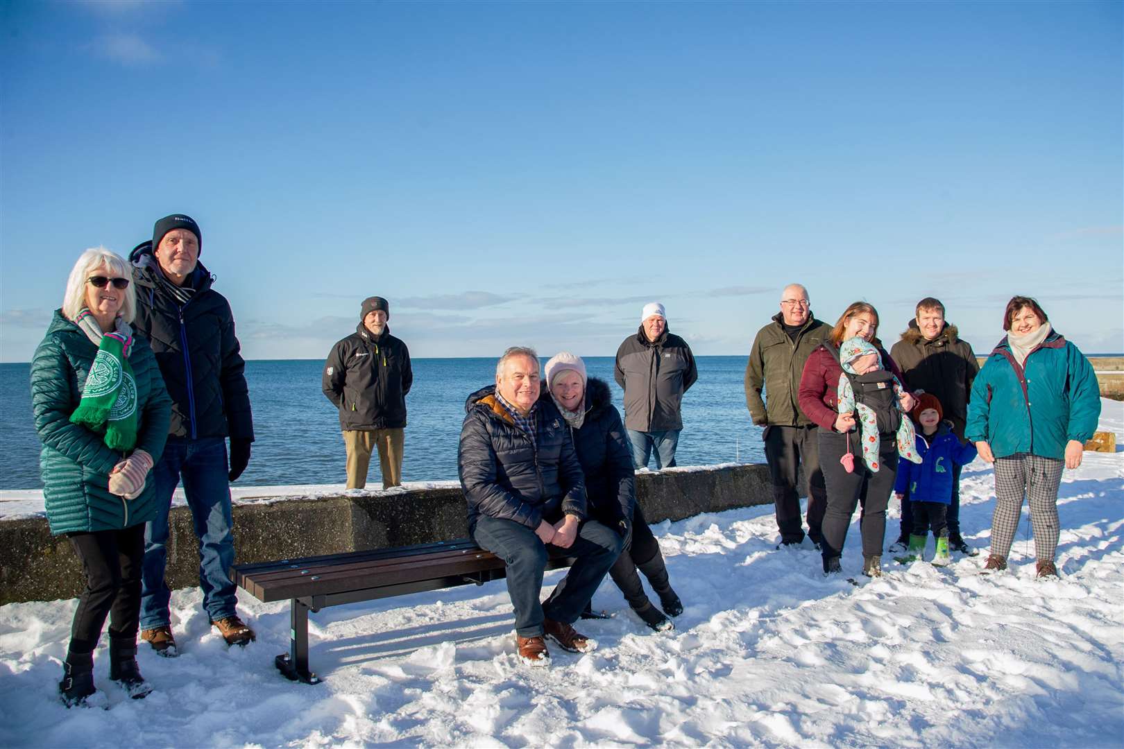 Portgordon Fireworks Committee chairman Kenny Gunn (seated) is joined by fellow committee members, fireworks night stall holders and members of the village's Covid support group at the new bench. Picture: Daniel Forsyth