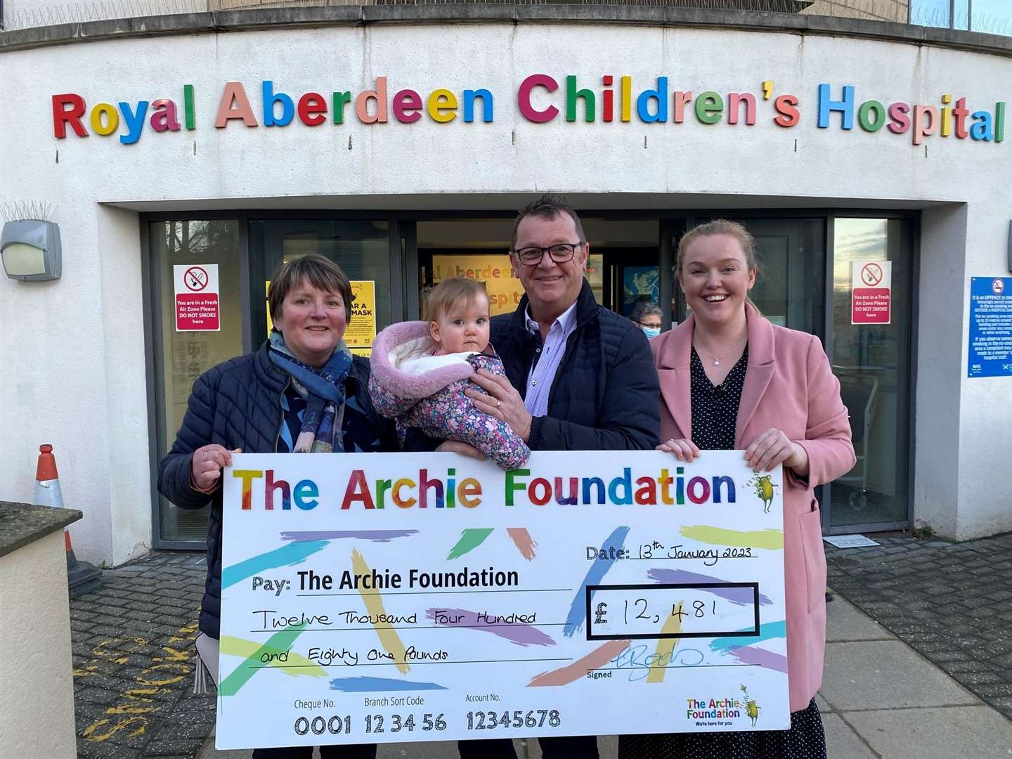 Shelly (right), her dad Charley and Rosie present a cheque for over £12,000 to The Archie Foundation after their charity auction.
