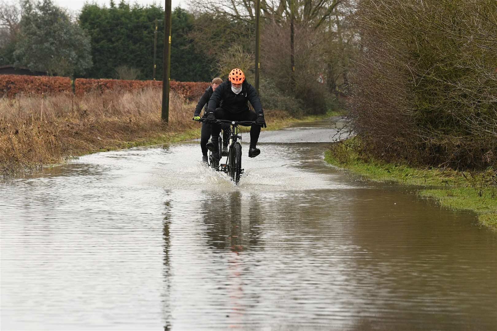 Cyclists make their way through flood water on Mountnessing Road in Billericay, Essex (Stefan Rousseau/PA)