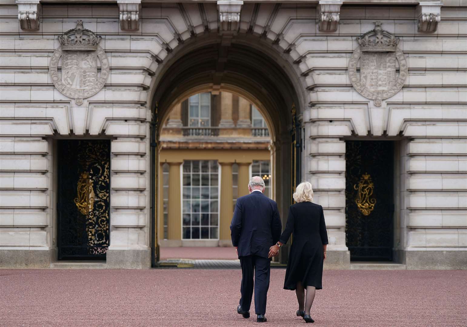 Charles and Camilla walk across the forecourt of Buckingham Palace (Yui Mok/PA)