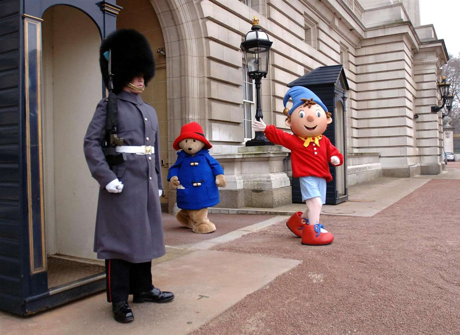 Noddy and Paddington Bear walk past a sentry at the front of Buckingham Palace in 2006 (Matthew Fearn/PA)