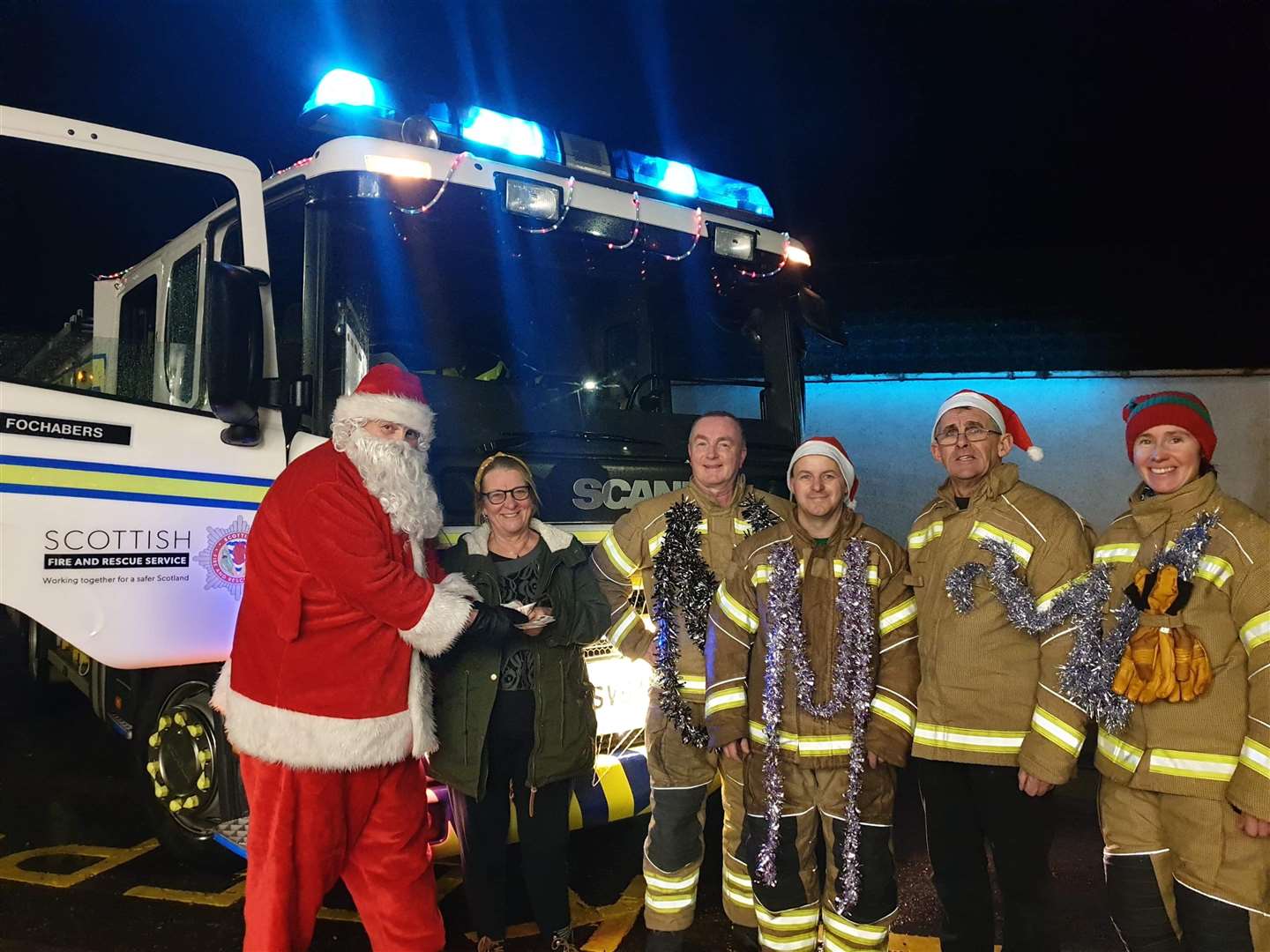 Santa accepts a donation from a householder as some of the fund-raising firefightrs look on. Picture: Fochabers fire station