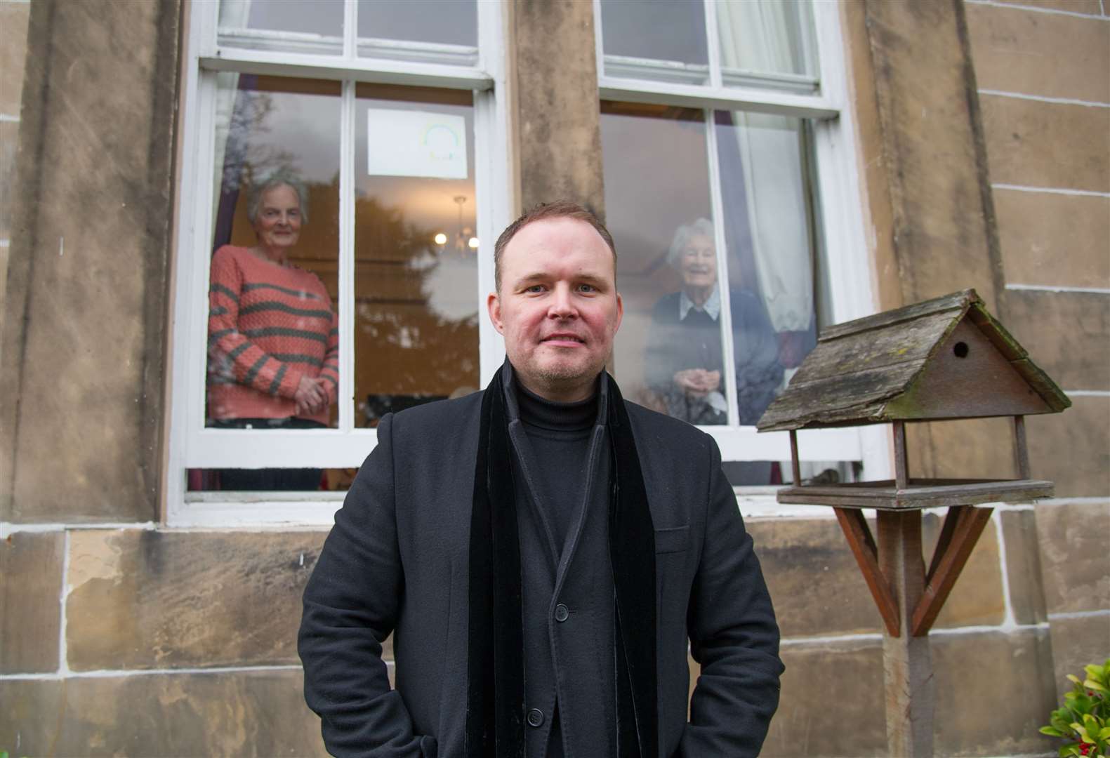 Singer Jason Porter outside Anderson's Care Home, on Elgin's Institution Road, as residents Winnie Masson (left) and Kay Corsie look on from the window. Picture: Becky Saunderson.