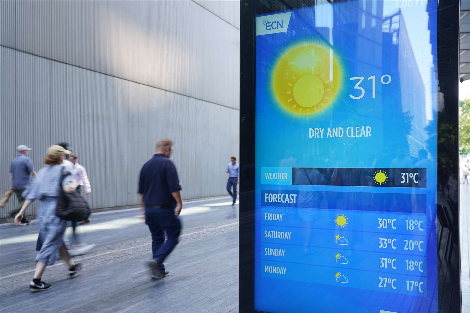 People walking past a digital weather report in Potters Field near Tower Bridge, London, on Thursday (PA)