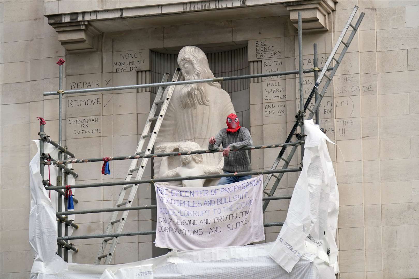 A man wearing a Spiderman mask on scaffolding surrounding the Prospero and Ariel statue by Eric Gill (Jonathan Brady/PA)