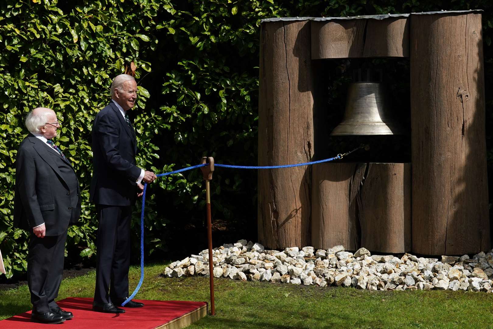 Michael D Higgins watches as Joe Biden rings the peace bell at Aras an Uachtarain in Phoenix Park (Brian Lawless/PA)