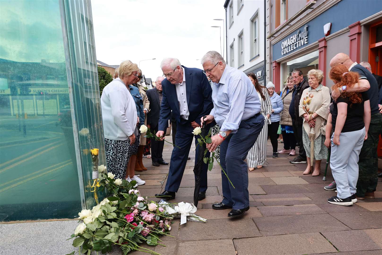 Michael Gallagher (centre), whose son Aiden died in the Omagh bombing, and Stanley McCombe whose wife Ann who was also killed, place flowers at the site of the bombing (Liam McBurney/PA)
