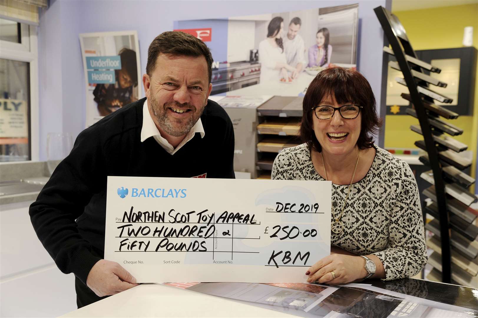 Keith Builders Merchants managing director Jeff Smith hands over a cheque for £250 for the Toy Appeal to Nicola McCart, senior accounts manager at the Northern Scot. Picture: Eric Cormack