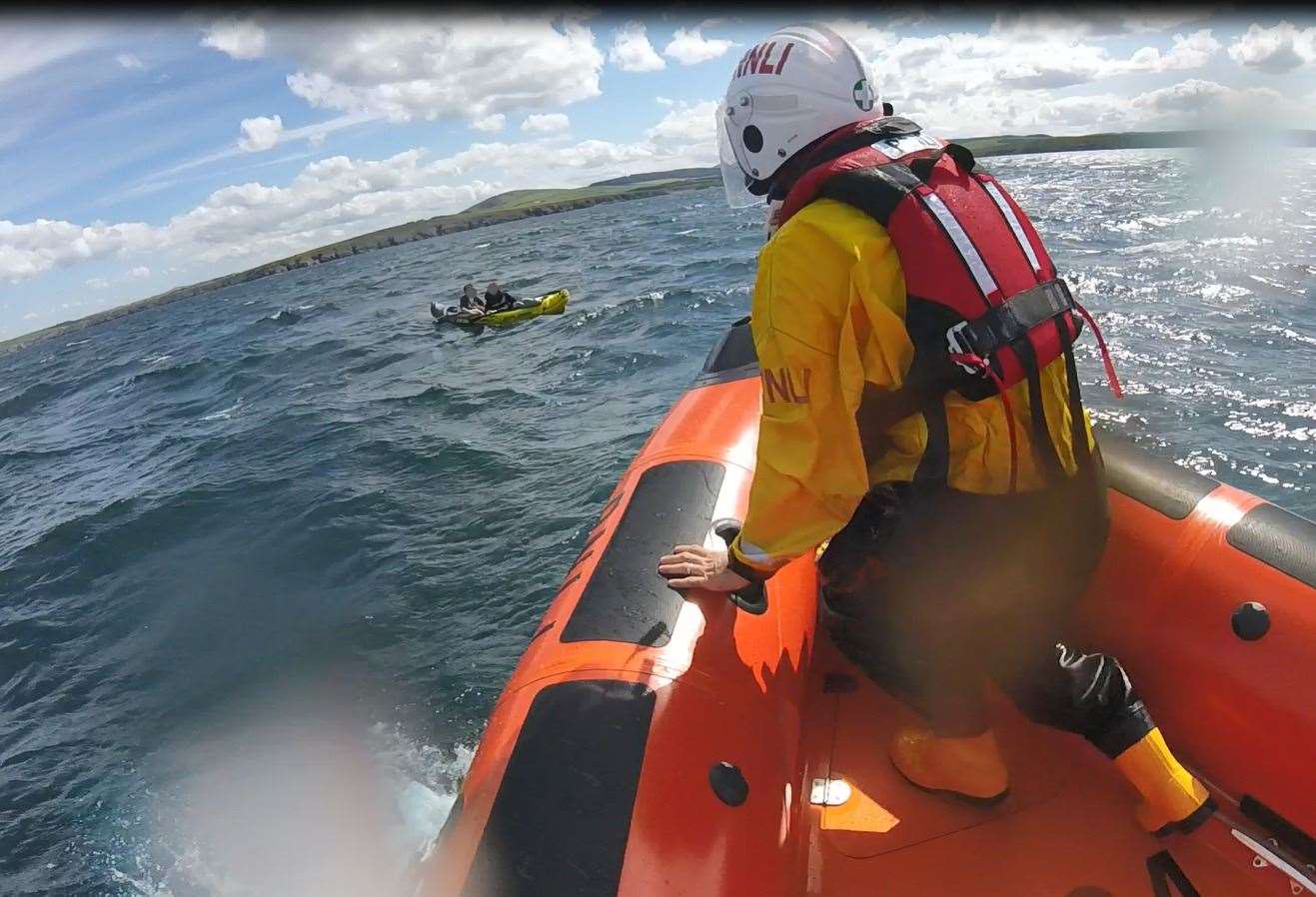 Volunteer lifeboat crew member Rob Smith at the bow of lifeboat B-804 helps two youngsters adrift off Portsoy, Image: RNLI